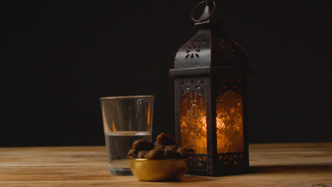 Tracking-Shot-of-Dates-Water-and-a-Lantern-On-Table